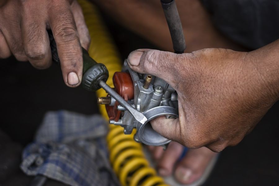 Mains d'un mécanicien sur un carburateur