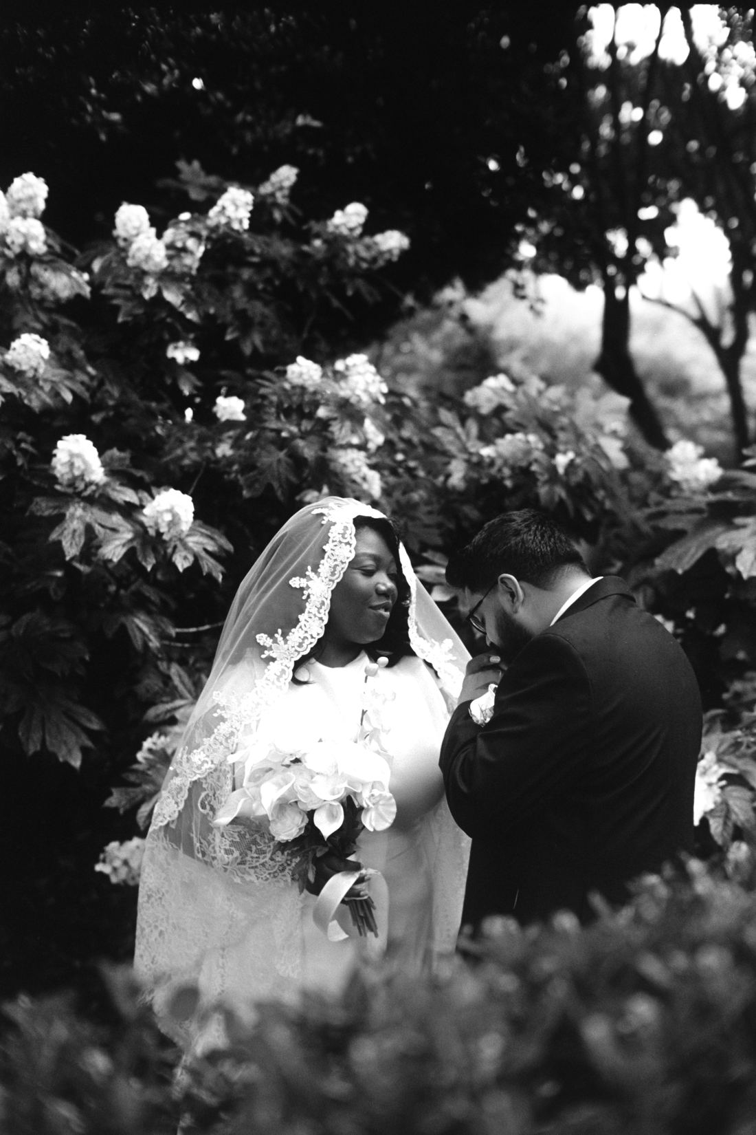 Le marié embrasse la main de la mariée, jardin fleuri